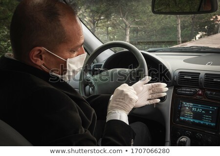 Stock photo: A Senior Adult Trying To Wear His Surgical Gloves In His Car For Protection