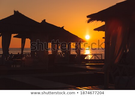 Stok fotoğraf: Thatched Housing Silhouette At Sunset