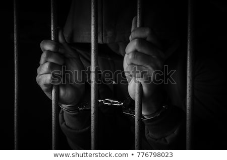 Foto stock: Handcuffed Man Behind Prison Bars