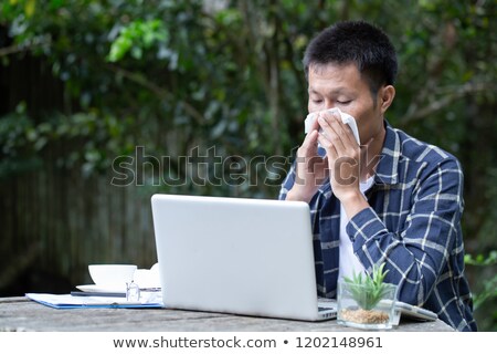 Stock photo: A Man Is Sitting In The Office At The Table Holding A Glass Of Coffee And A Pen In His Hand And Wor