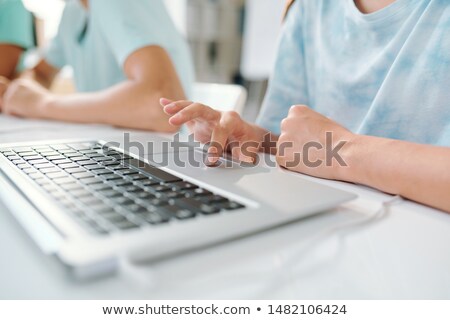 Young Person Pressing Button On Laptop Pad While Sitting By Desk Foto stock © Pressmaster