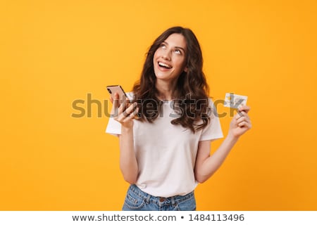 Stockfoto: Happy Young Girl Posing Over Yellow Wall Background Holding Shopping Bags