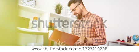 Stok fotoğraf: A Man In The Office Stands Near The Shelf And Scrolls Through The Folder With The Documents