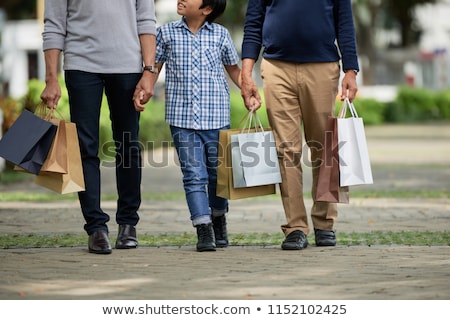 Stok fotoğraf: Crop Boy Walking With Men After Shopping