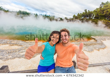 Foto stock: New Zealand Happy Tourist Couple Doing Thumbs Up At Famous Attraction Travel Destination Champagne