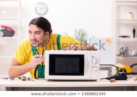 Stock photo: Young Contractor Repairing Oven In Kitchen