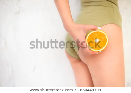 Stockfoto: Young Girl Holding Orange In Her Hand By The Hips Cellulite Li