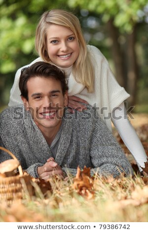 Zdjęcia stock: A Young Couple Lying Down On The Grass A Mushrooms Basket Is On The Ground