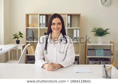 Foto stock: Medical Specialist Wears White Gown With Stethoscope Works In Hospital Makes Notes Poses At Own C