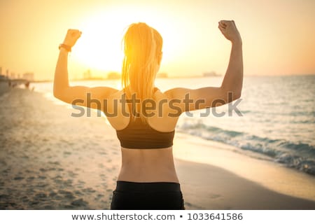 [[stock_photo]]: Strong Fitness Woman Flexing Biceps On Sunset