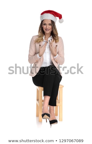 Stockfoto: Happy Businesswoman Wearing Santa Hat Sits On Wooden Chair