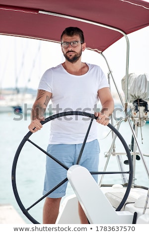 Foto stock: Happy Guy Behind Wheel Of Sailboat