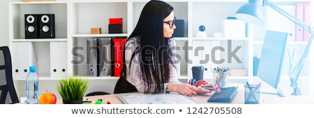 Сток-фото: A Young Girl In Glasses Stands Near The Table Holds A Marker In Her Hand And Prints On The Keyboard