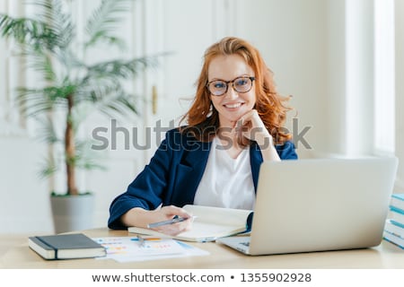 Foto stock: Photo Of Successful Ginger Female Freelancer Has Remote Work Watches Webinar Online On Laptop Compu