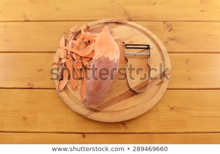 Stockfoto: Sweet Potato With Vegetable Peeler On A Chopping Board