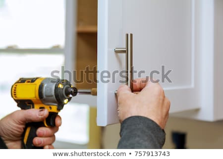 Stockfoto: Male Handyman Installing Cabinet Door