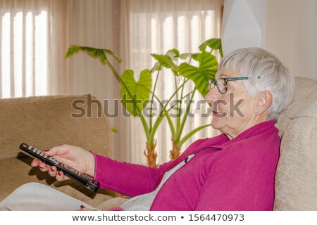 Stock photo: Senior Woman Watching Tv On Her Sofa At Home