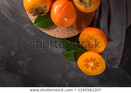 Stockfoto: Ripe Persimmon Fruits In A Cork Plate