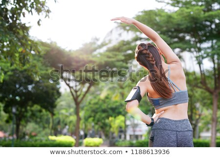 Stock fotó: Anonymous Sportswoman With Armband Stretching In Park