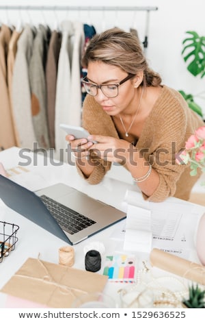 Pretty Young Female Fashion Designer Scrolling In Smartphone Foto stock © Pressmaster