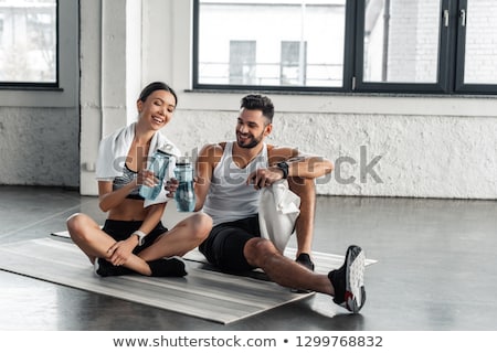 Stockfoto: Couple With Bottles Exercise Mat And Towel In Gym