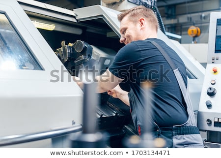 Foto stock: Experienced Worker Changing Tool Setup Of Lathe Machine