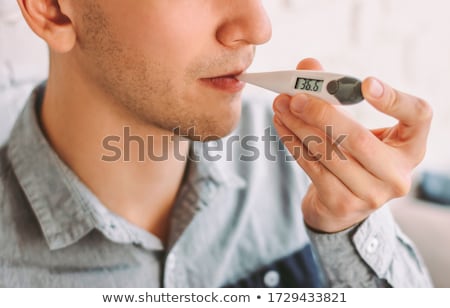 Foto d'archivio: Man Measuring Oral Temperature By Thermometer