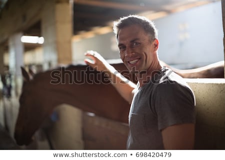 Stok fotoğraf: Man Caressing The Brown Horse In The Stable