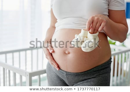 Foto stock: Pregnant Woman Holding A Baby Booties