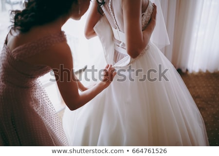 Foto stock: Bridesmaids Help To Wear A Wedding Dress