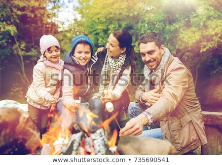 Foto stock: Happy Family Roasting Marshmallow Over Campfire