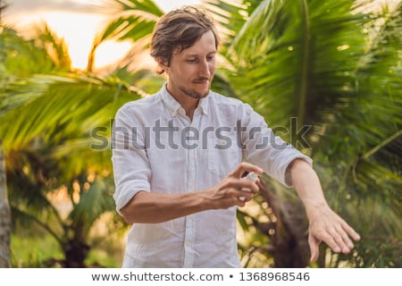 [[stock_photo]]: Young Man Spraying Mosquito Insect Repellent In The Forrest Insect Protection