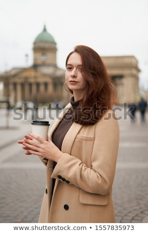 Stock photo: Woman Model On The Street In A Gray Coat With Long Dark Hair Against A Solid Wall