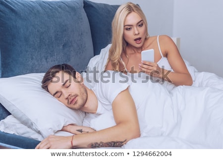 Foto stock: Man Using Smartphone While Girlfriend Is Sleeping