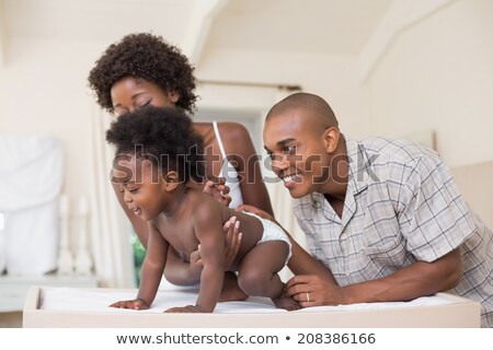 Сток-фото: Side View Of Happy African American Parents With Their Cute Children Reading Storybook On The Sofa I