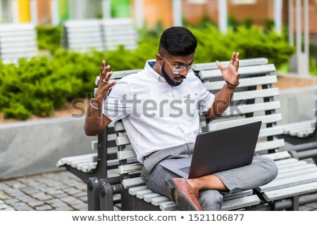 Stok fotoğraf: Angry Businessman Sitting On Bench With Laptop