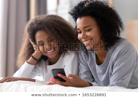 Foto stock: Two Young Women Using Mobile Phone On The Bed In The Room