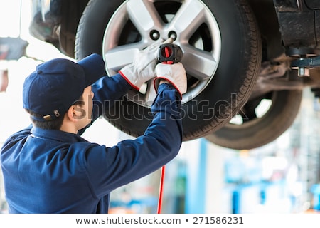 Stok fotoğraf: Mechanician Changing Car Wheel In Auto Repair Shop