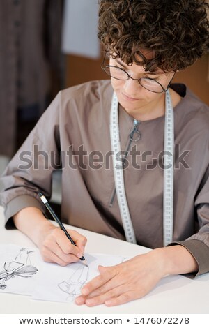 Young Serious Female Sketching New Fashion Models On Paper Foto stock © Pressmaster