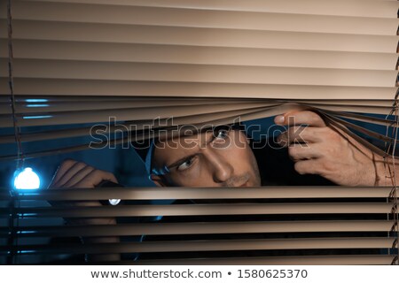 Foto stock: Looking Through Blinds With A Flashlight