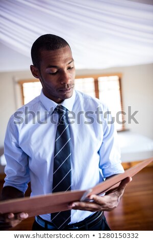 Stockfoto: Attentive Male Supervisor Looking At File In Hotel