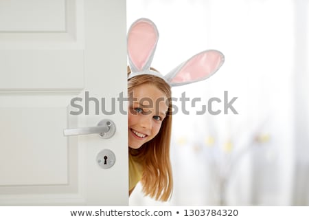 Zdjęcia stock: Happy Girl With Easter Bunny Ears Peeking Out Door