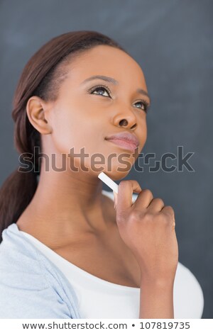 Stockfoto: Black Woman Looking Up While Holding A Chalk In A Classroom