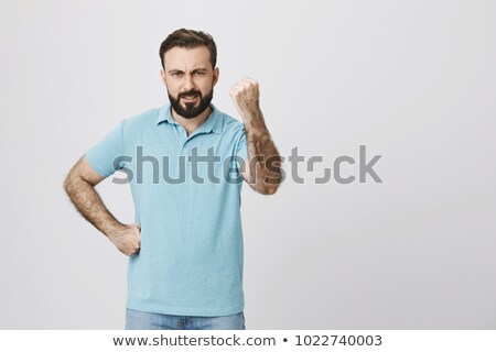 Foto stock: Angry Bearded Young Man Standing And Showing Fist