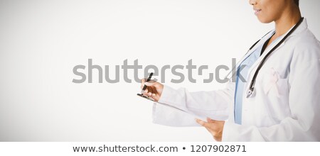 Сток-фото: Female Doctor Wearing Breast Cancer Awareness Pink Ribbon Writing On A Note Pad On A White Backgroun