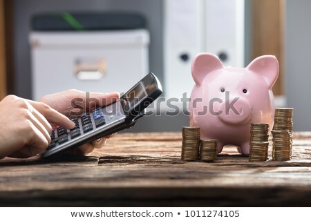 Foto d'archivio: Piggy Bank And Stacked Coins On Wooden Desk