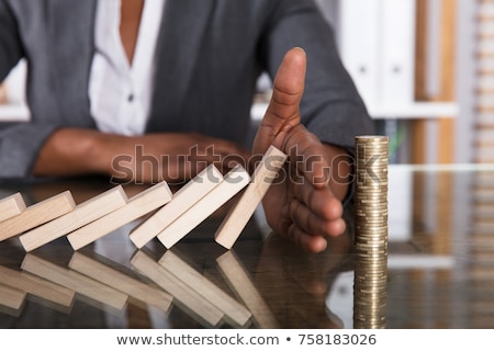 Stock photo: Person Stopping Dominos From Falling With Stacked Coins