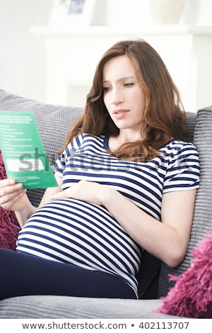 Stock photo: Concerned Pregnant Woman Sitting On Sofa Reading Leaflet