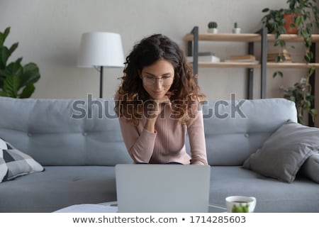 Сток-фото: Smiling Woman Sitting On Sofa In Front Of Laptop