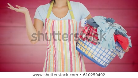 商業照片: Woman In Apron With Laundry Against Blurry Pink Wood Panel